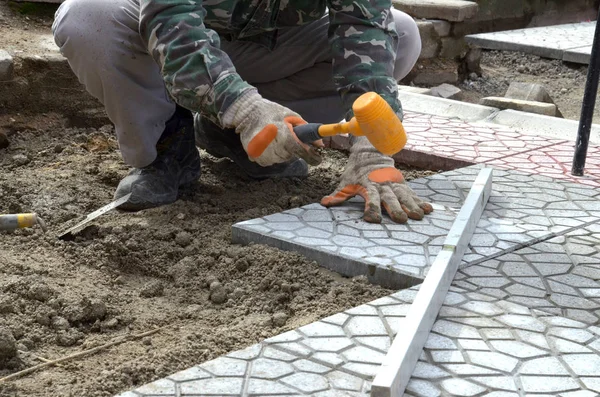 Hands of a builder laying new paving stones carefully placing on