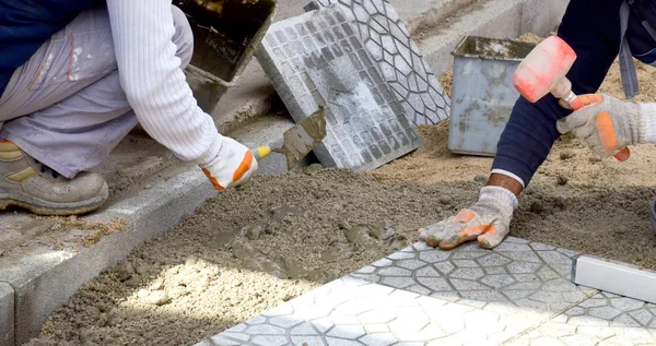 Mains d'un constructeur pose de nouvelles pierres de pavage soigneusement placer sur — Photo