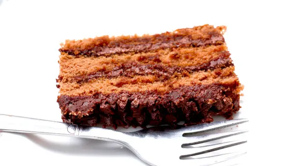 Fatia de bolo de chocolate com garfo no fundo branco — Fotografia de Stock