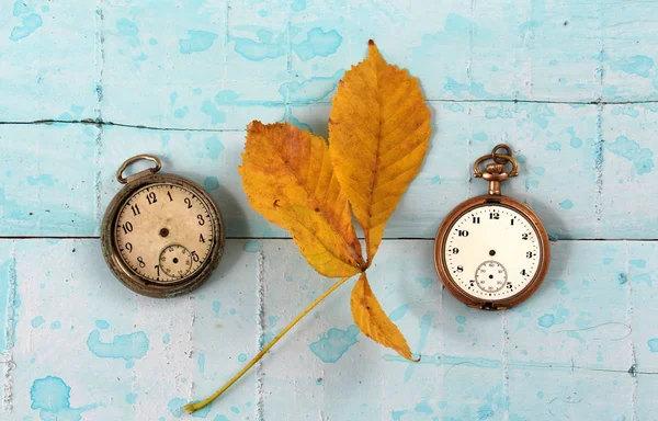 Relógio de bolso vintage e folhas de outono em um suraface de madeira pintado azul — Fotografia de Stock