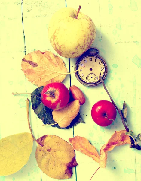 apples,clock, leaves, on blue paint wood background