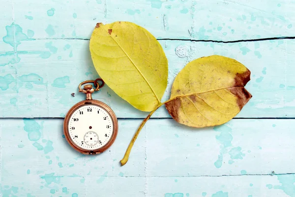 Relógio vintage e folhas de nogueira de Outono em fundo de madeira pintura azul — Fotografia de Stock