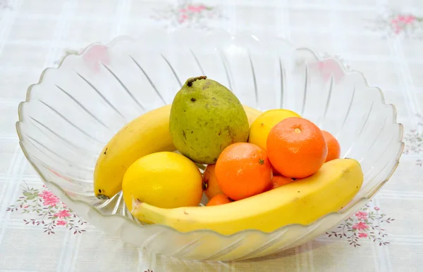 Pera, limones, naranjas y plátanos en un tazón de cristal grande — Foto de Stock