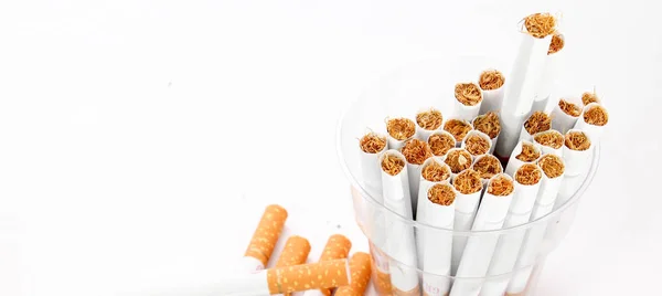 Cigarettes dans une tasse jetable et horloge vintage sur fond blanc — Photo