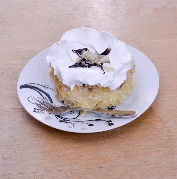 Mandel tårta i en tallrik på trä bakgrund — Stockfoto