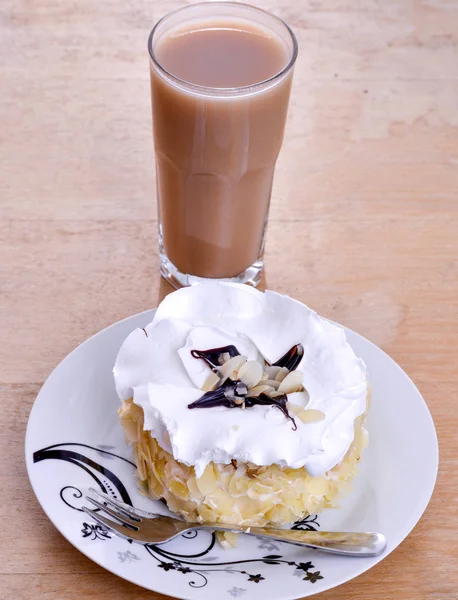 Κέικ αμυγδάλου σε ένα πιάτο σε ξύλινο φόντο και γυαλί από ένα Μπόζα — Φωτογραφία Αρχείου