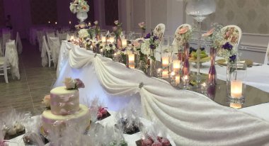 Gelin ve damat masası çiçeklerle ve mumlarla süslenmiş.