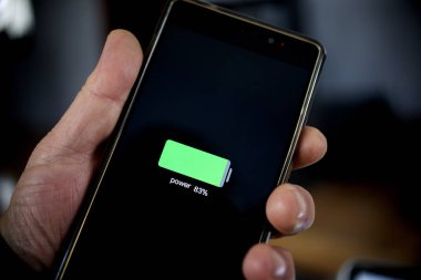 El ele tutuşan akıllı telefon şarj üstüne pil seviyesini gösteriyor