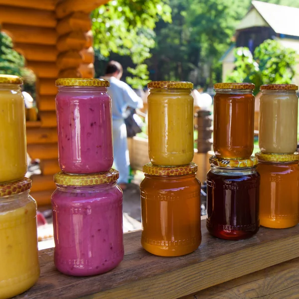 Üvegek, mézzel piacon. Házi készítésű méz. különböző edényben a fen — Stock Fotó