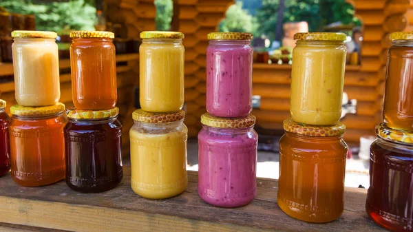 Üvegek, mézzel piacon. Házi készítésű méz. különböző edényben a fen — Stock Fotó