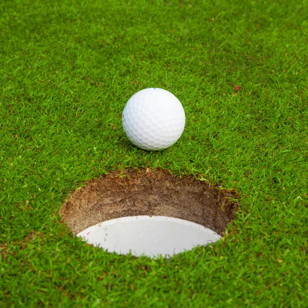 Golf ball on lip of cup. Golf ball on green grass in golf course — Stock Photo, Image