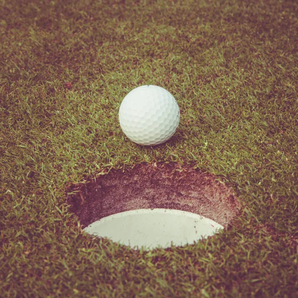 Bola de golfe no lábio do copo. Bola de golfe na grama verde no campo de golfe — Fotografia de Stock