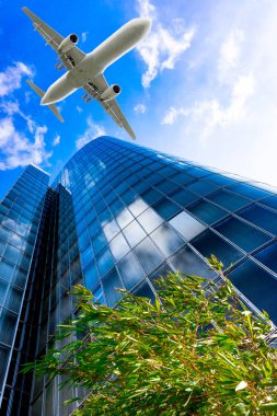 Mavi gökyüzü uçan bir uçak ile gökdelenler