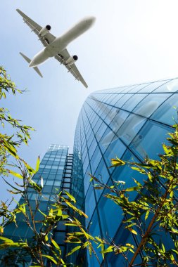 Mavi gökyüzü uçan bir uçak ile gökdelenler