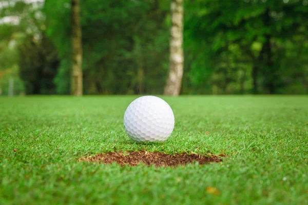 Golf ball on green meadow. golf ball on lip of cup — Stock Photo, Image
