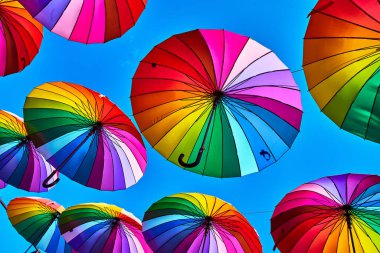 Gökkuşağı gökyüzü arka plan üzerinde şemsiye. Birçok renkli şemsiyeler. umb