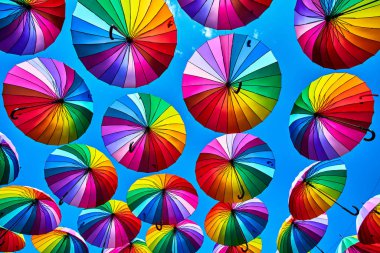 Gökkuşağı gökyüzü arka plan üzerinde şemsiye. Birçok renkli şemsiyeler. umb