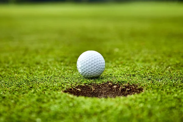 Balle de golf sur le green. balle de golf sur lèvre de tasse — Photo