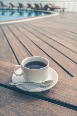 Fincan havuzun yanındaki masada. Beyaz seramik kahve fincanı 
