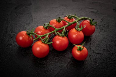 Siyah arka planda taze kiraz domatesleri.