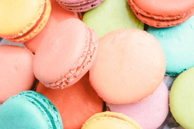 Pembe arka planda bir sürü Fransız renkli badem kurabiyesi.