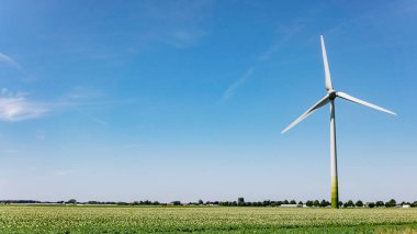 Yaz tarlasında yel değirmeni. Yeşil alanda değirmen. Güzel manzara ve değirmen.