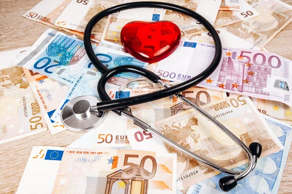 Концепция стоимости медицинских расходов. Стетоскоп и фигура сердца на банкнотах евро — стоковое фото