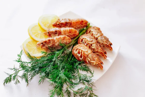 Camarones en un plato con limón y eneldo. Fondo blanco — Foto de Stock