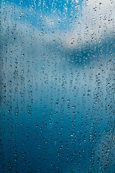 Gotas de chuva na janela fundo azul — Fotografia de Stock