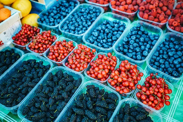 Een mix van verse bessen op de markt, aardbeien, bosbessen, frambozen, bramen, kersen en rode bessen — Stockfoto