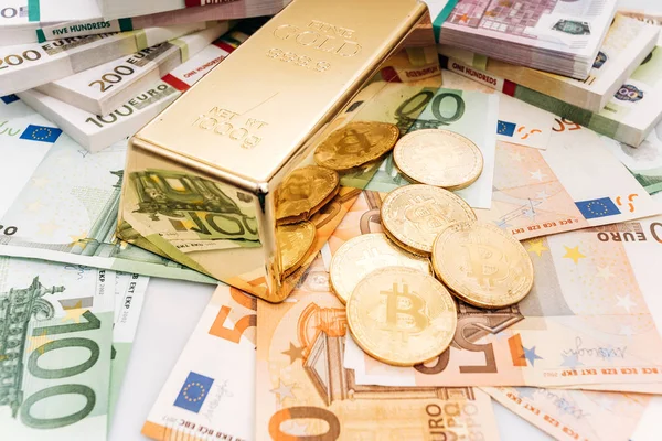 Bitcoin BTC Monedas de oro con billetes de billetes de euro y lingotes de oro. Bitcoin y oro yacen en billetes en euros —  Fotos de Stock