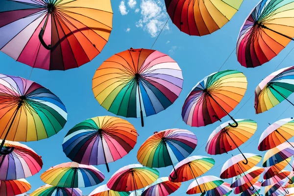 Guarda-chuvas na cor do arco-íris no fundo do céu azul — Fotografia de Stock