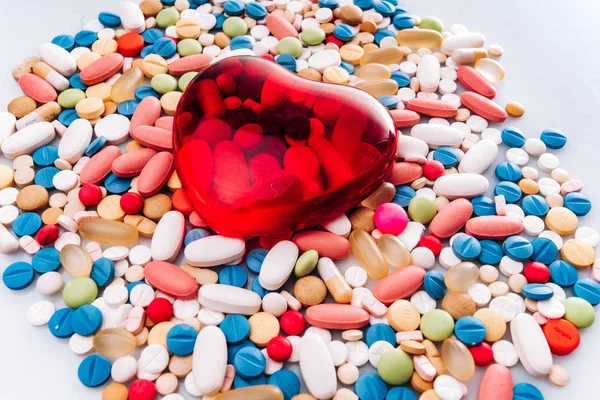 心臓の形をした薬の丸薬、錠剤、フィギュアを割り当てます。背景に丸薬さまざまな薬の錠剤や錠剤のヒープ白い背景に異なる色。健康 — ストック写真