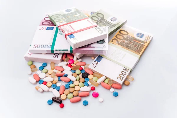 Разноцветные таблетки с банкнотами евро на белом фоне — стоковое фото
