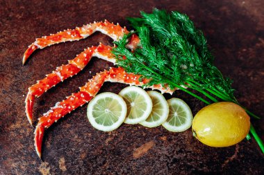 Masanın üzerinde yengeç, limon ve bitkiler var. Kırmızımsı renk tablosu.