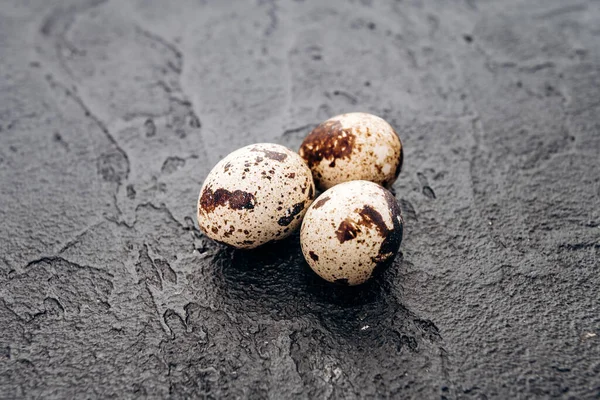 Перепелині яйця на чорному тлі. Кілька перепелиних яєць лежать на фоні чорного каменю — стокове фото