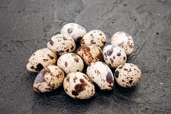 Ovos de codorniz sobre um fundo preto. Vários ovos de codorna estão em um fundo de pedra preta — Fotografia de Stock