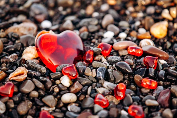 Corazones rojos en una playa de guijarros. Fondo de piedras y corazones — Foto de Stock