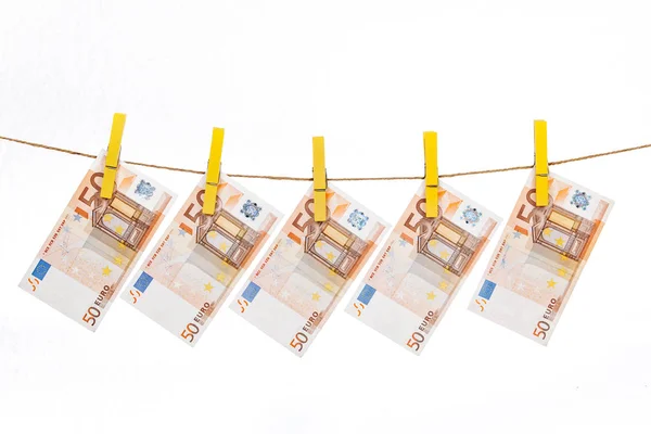 Az eurobankjegyeket sárga ruhacsipeszekkel fehér alapon kötélhez erősítik. — Stock Fotó
