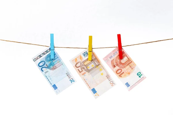 Az eurobankjegyeket különböző színű ruhacsipeszekkel, fehér alapon kötélhez erősítik. — Stock Fotó