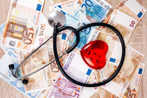 O conceito do custo das despesas médicas. O estetoscópio e a figura do coração nas notas de euro — Fotografia de Stock