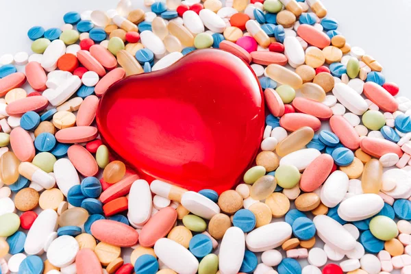 Różne leki farmaceutyczne pigułki, tabletki i figurka w kształcie serca. Pigułki w tle. Kupa różnych tabletek i pigułek różnych kolorów na białym tle. Zdrowie — Zdjęcie stockowe