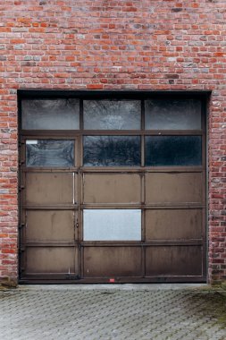 Tuğla duvarı ve asfalt yolu olan büyük garaj kapısı.