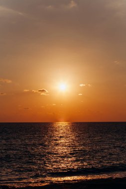 Denizin üzerinde güzel bir gün batımı. Sudaki günbatımının yansıması..