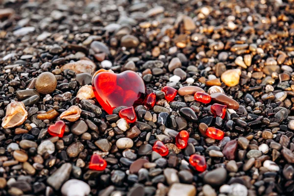 Corazones rojos en una playa de guijarros. Fondo de piedras y corazones — Foto de Stock