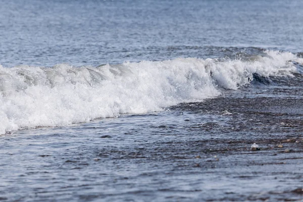 Olas en la playa. Una oleada de agua en tierra . — Foto de Stock