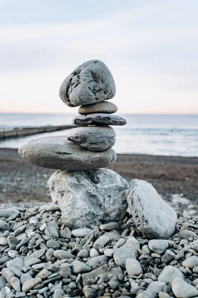 La figura de piedras de pie uno sobre el otro, en la playa contra el mar. — Foto de Stock