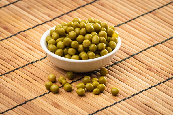 Guisantes verdes enlatados en el tazón sobre fondo de madera —  Fotos de Stock