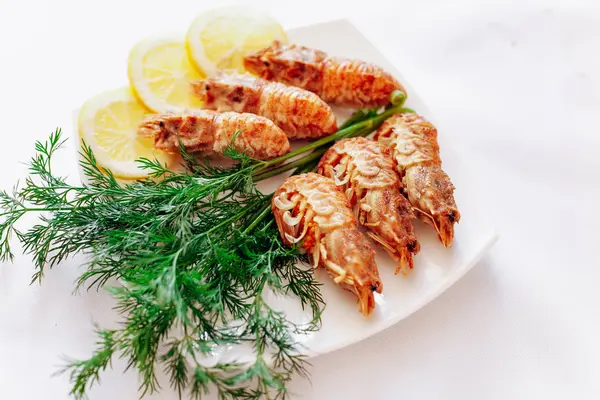 Camarones en un plato con limón y eneldo. Fondo blanco — Foto de Stock