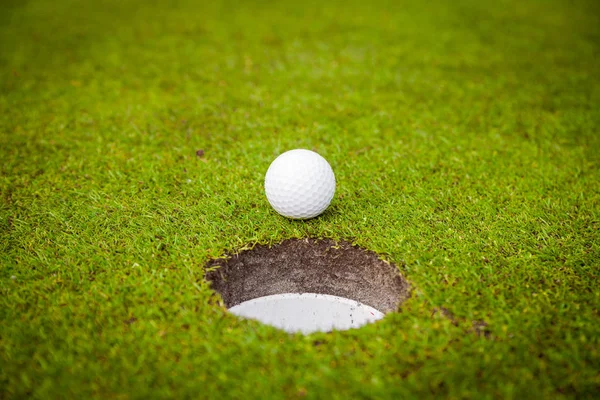カップの縁にゴルフ ・ ボール。ゴルフ場の緑の草の上ゴルフ ボール — ストック写真